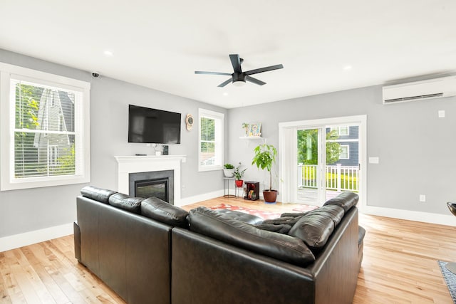 living room with ceiling fan, a wall unit AC, and light hardwood / wood-style floors