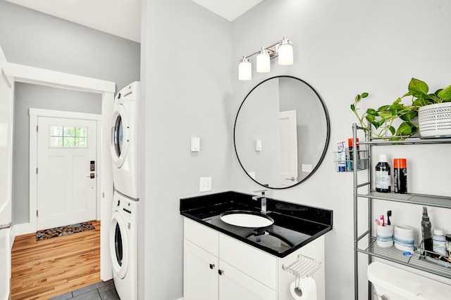 laundry area featuring light hardwood / wood-style flooring, sink, and stacked washer / drying machine