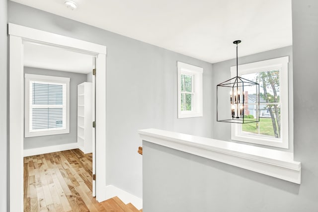 hall with light hardwood / wood-style flooring and a notable chandelier