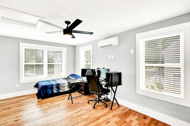 bedroom with light hardwood / wood-style flooring, ceiling fan, and a wall mounted air conditioner