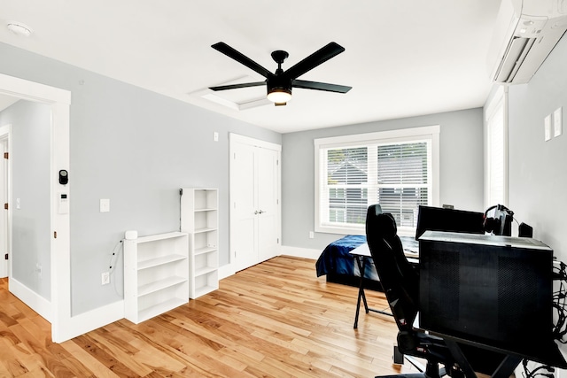 office space featuring a wall mounted AC, light wood-type flooring, and ceiling fan