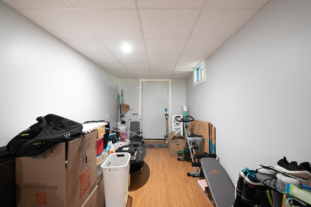 exercise area with light wood-type flooring and a paneled ceiling