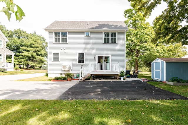 rear view of house featuring ac unit, a yard, and a shed