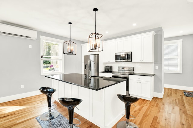 kitchen with a kitchen bar, stainless steel appliances, an AC wall unit, and light wood-type flooring