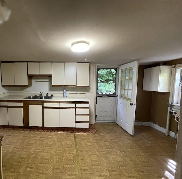 kitchen featuring light parquet flooring, white cabinetry, and sink