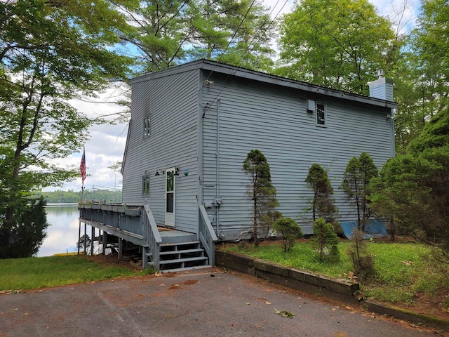 view of side of home with a yard and a deck with water view