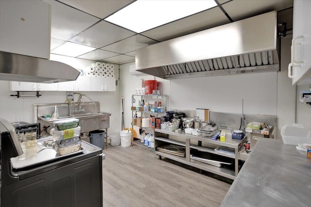 kitchen featuring white cabinets, light hardwood / wood-style flooring, stainless steel counters, and a drop ceiling