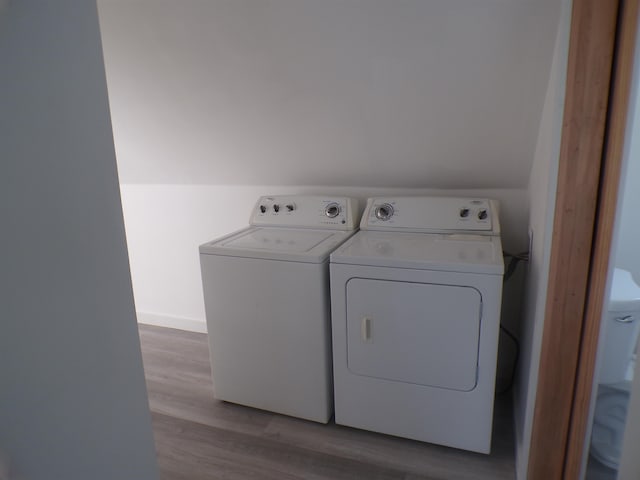 laundry area featuring washing machine and clothes dryer and light hardwood / wood-style floors