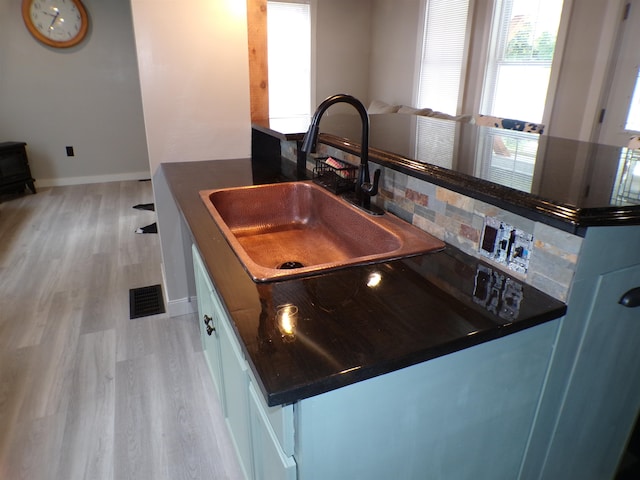 kitchen featuring white cabinetry, light hardwood / wood-style flooring, backsplash, and sink