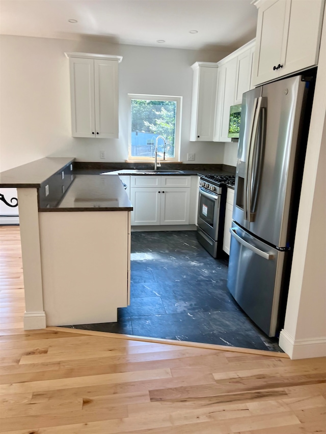 kitchen featuring wood-type flooring, appliances with stainless steel finishes, sink, and white cabinets