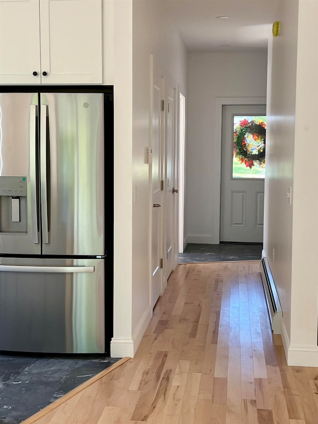 corridor with a baseboard heating unit and light hardwood / wood-style floors