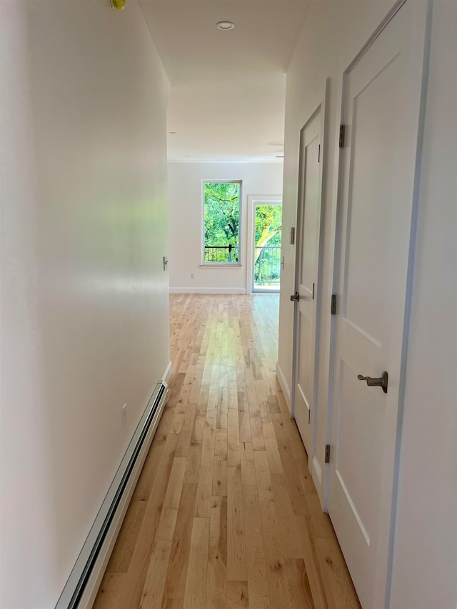 corridor featuring a baseboard radiator and light wood-type flooring