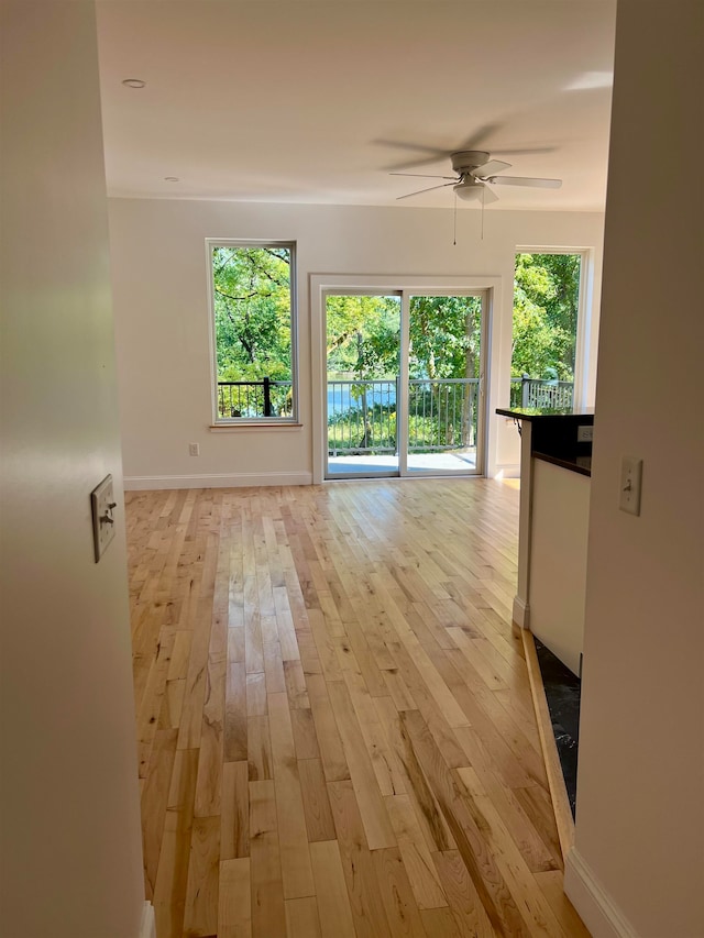 unfurnished living room with ceiling fan, a healthy amount of sunlight, and light wood-type flooring