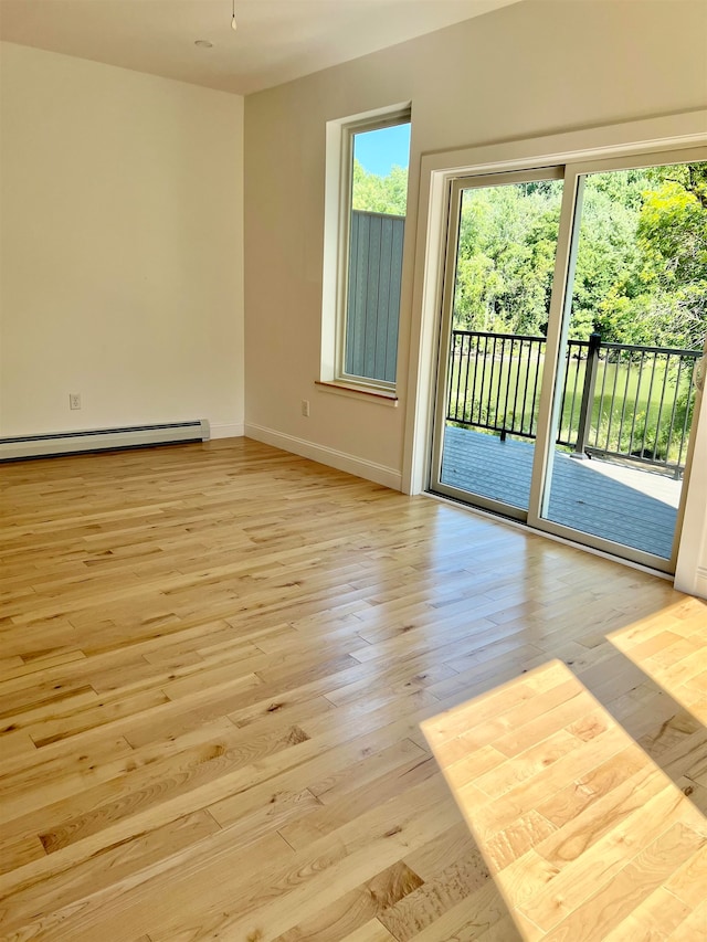 spare room featuring a baseboard heating unit and light hardwood / wood-style floors