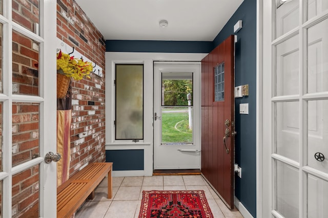 doorway to outside featuring brick wall and light tile patterned floors