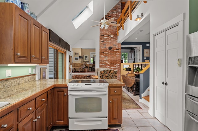 kitchen featuring light tile patterned floors, vaulted ceiling with skylight, kitchen peninsula, ceiling fan, and white electric range oven