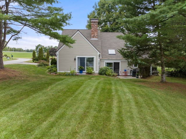 rear view of house with a lawn and a patio