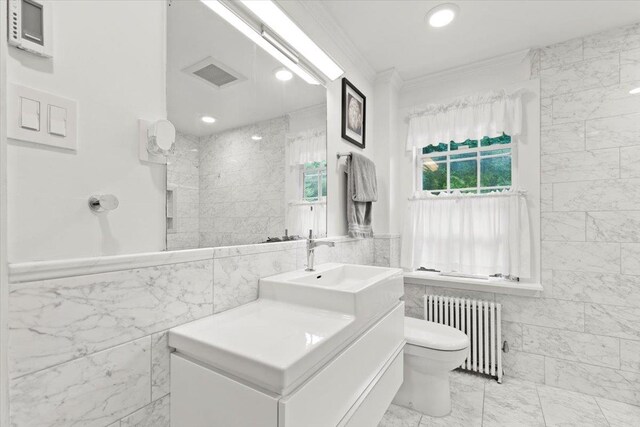 bathroom with toilet, ornamental molding, vanity, radiator, and tile walls