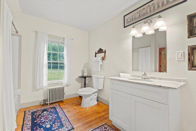 bathroom featuring toilet, hardwood / wood-style flooring, radiator, and vanity