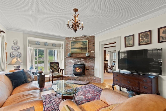 living room with a fireplace, crown molding, light hardwood / wood-style flooring, a chandelier, and a wood stove