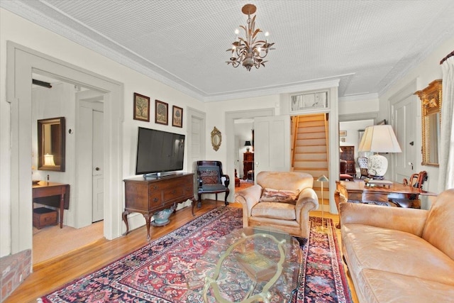 living room featuring light wood-type flooring, a chandelier, and ornamental molding