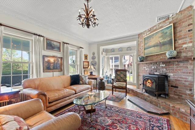 living room with crown molding, wood-type flooring, and a wood stove