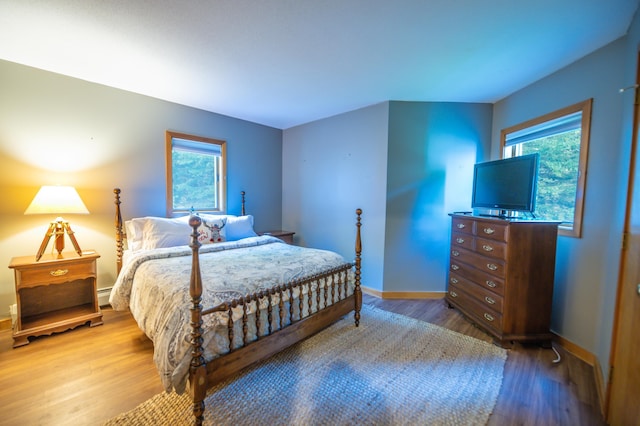 bedroom featuring baseboard heating, baseboards, and wood finished floors