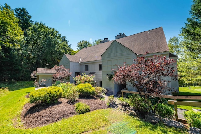 view of side of home with a yard, board and batten siding, a chimney, and a shingled roof