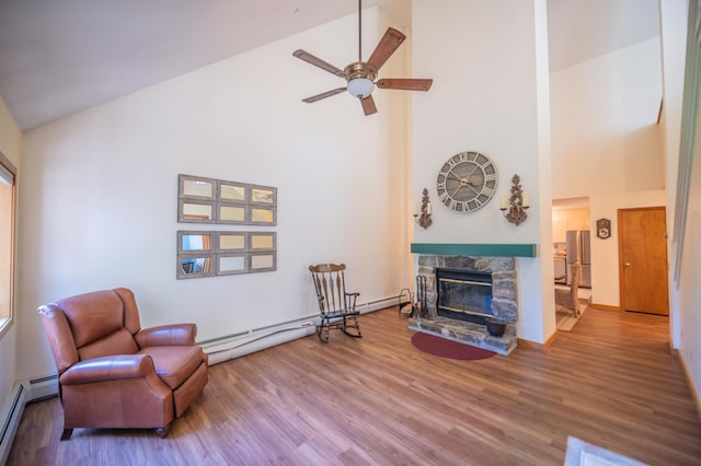 living area with high vaulted ceiling, baseboard heating, wood finished floors, and a fireplace