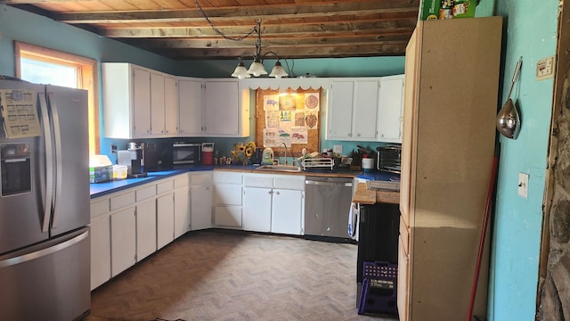 kitchen featuring parquet flooring, sink, beamed ceiling, stainless steel appliances, and white cabinets