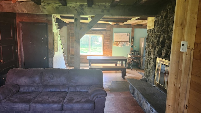 living room with beamed ceiling and a stone fireplace