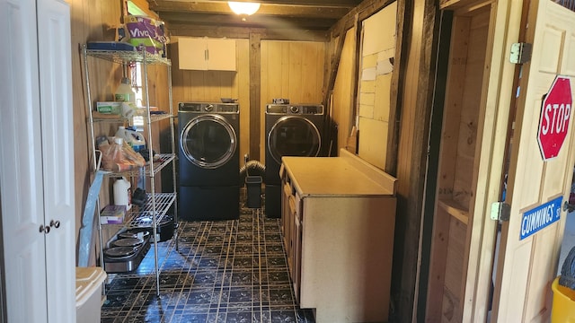 laundry room featuring washer and dryer, cabinets, and wood walls