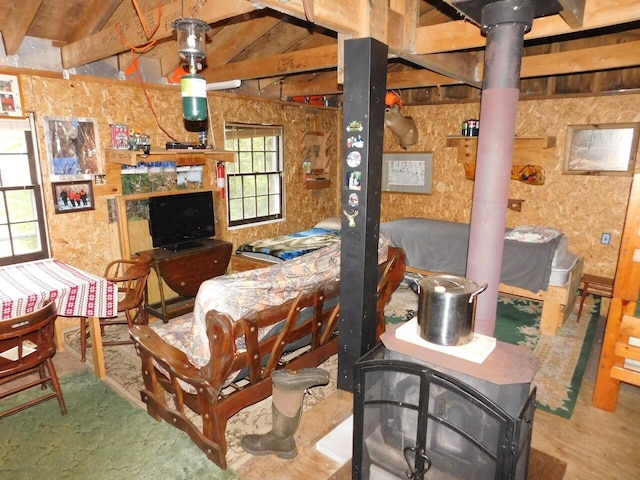 living area with a wood stove and vaulted ceiling with beams