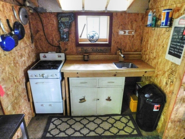 kitchen with wood walls, sink, and white range