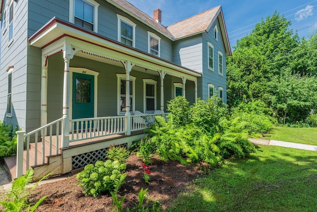 victorian home with a chimney, a front lawn, and covered porch