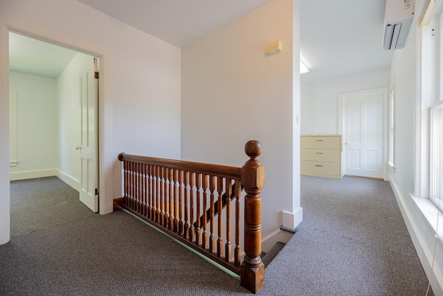hall with carpet flooring, an upstairs landing, baseboards, and a wall unit AC