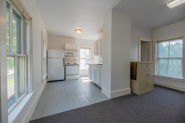kitchen featuring a sink, white cabinets, white appliances, and light carpet