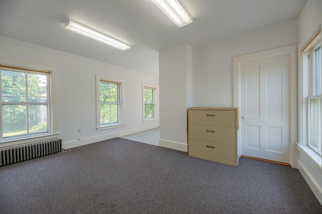 carpeted empty room featuring baseboards and radiator