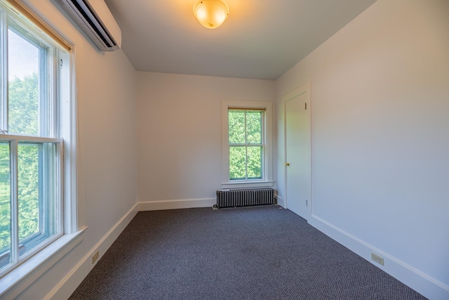 unfurnished room featuring radiator heating unit, baseboards, dark carpet, and a wall mounted air conditioner