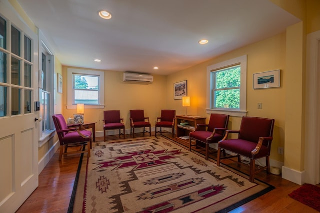 sitting room with recessed lighting, a wall mounted AC, baseboards, and wood finished floors