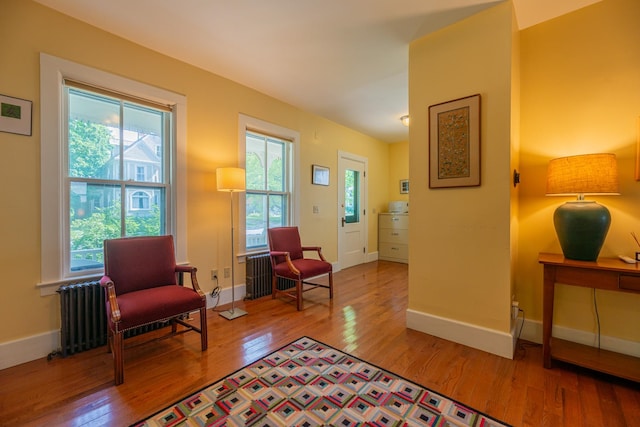 sitting room featuring wood-type flooring, baseboards, and radiator