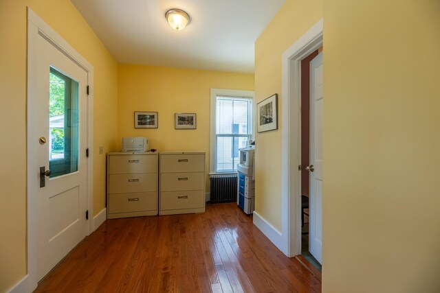 hall with dark wood-type flooring, radiator heating unit, and baseboards