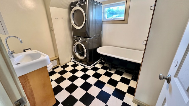 bathroom with stacked washer / dryer, vanity, and a bath