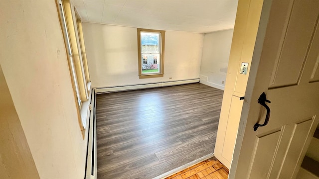 unfurnished room featuring baseboard heating and hardwood / wood-style floors