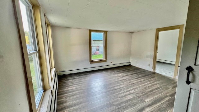 spare room featuring baseboard heating and wood-type flooring