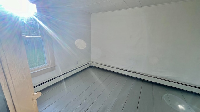 empty room featuring baseboard heating and wood-type flooring