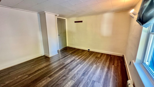 spare room featuring dark wood-type flooring and a baseboard heating unit