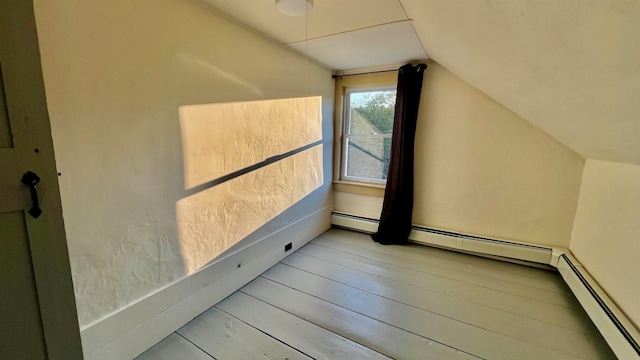 additional living space with lofted ceiling, light hardwood / wood-style flooring, and baseboard heating