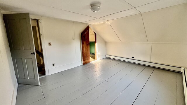 additional living space with lofted ceiling, hardwood / wood-style floors, and a baseboard radiator