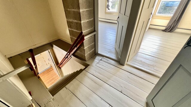 stairway with baseboard heating and hardwood / wood-style floors